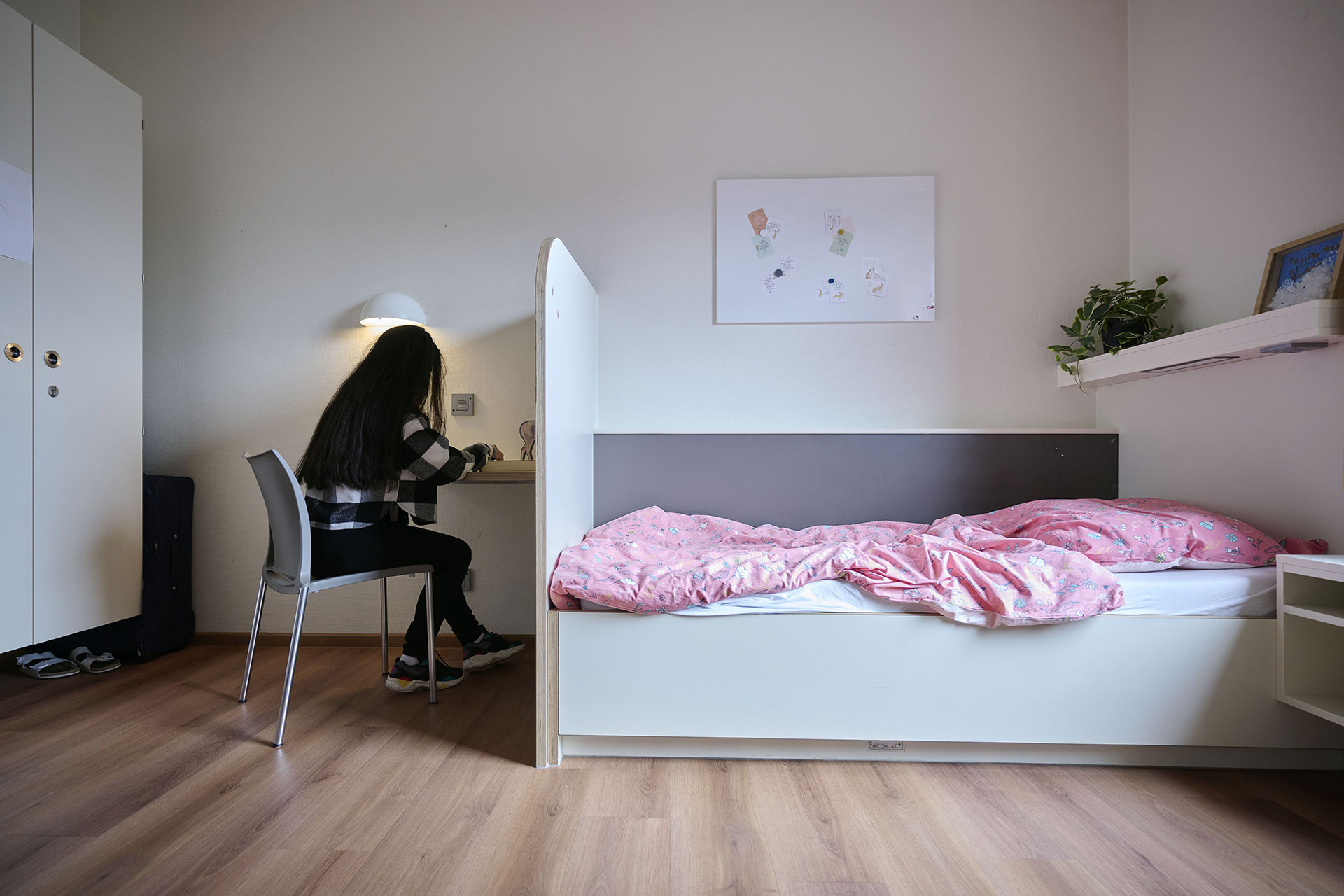 Ein junges Mädchen sitzt in einem Patientenzimmer am Schreibtisch