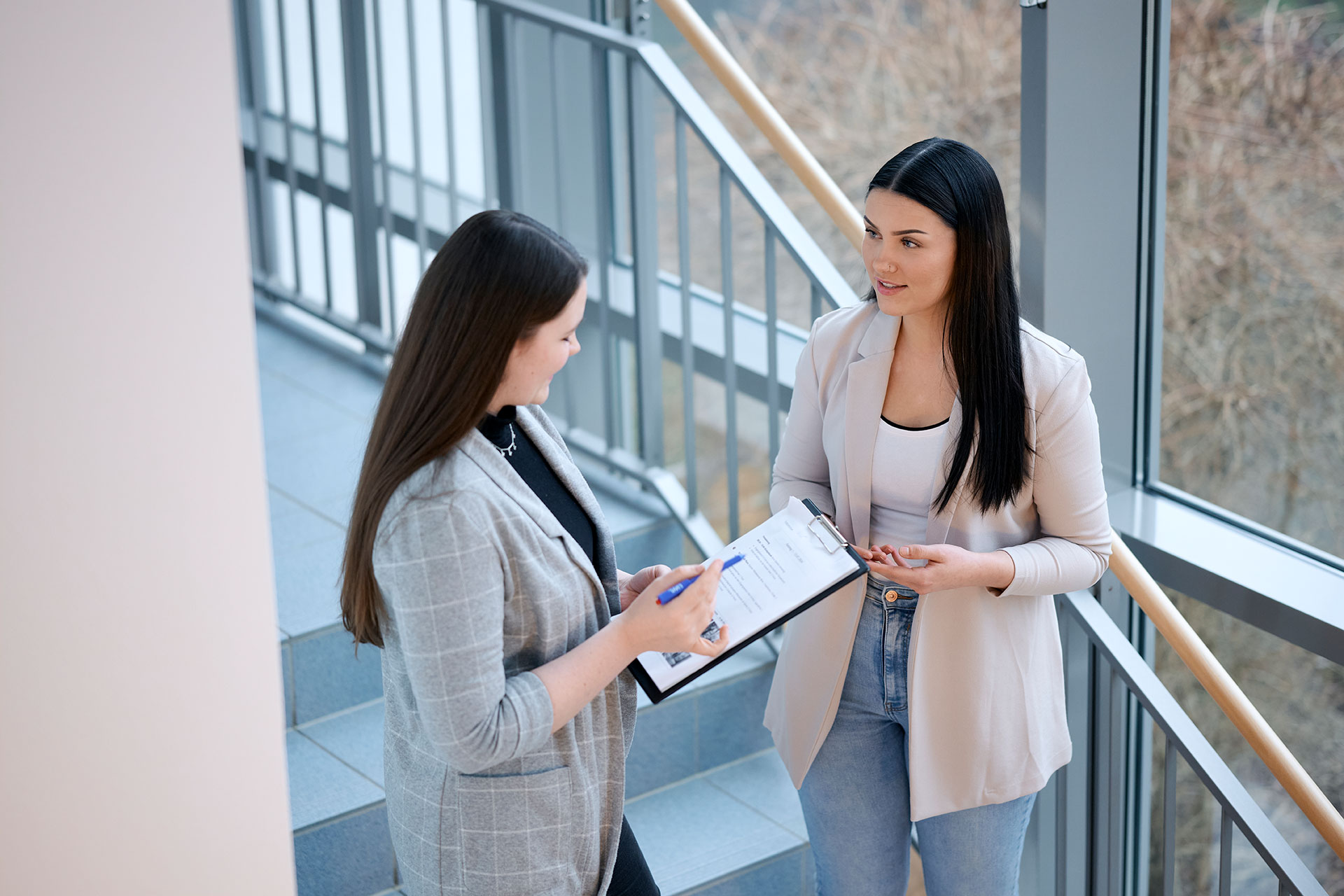 Das Bild zeigt zwei Kolleg:innen, die über ein Dokument sprechen.