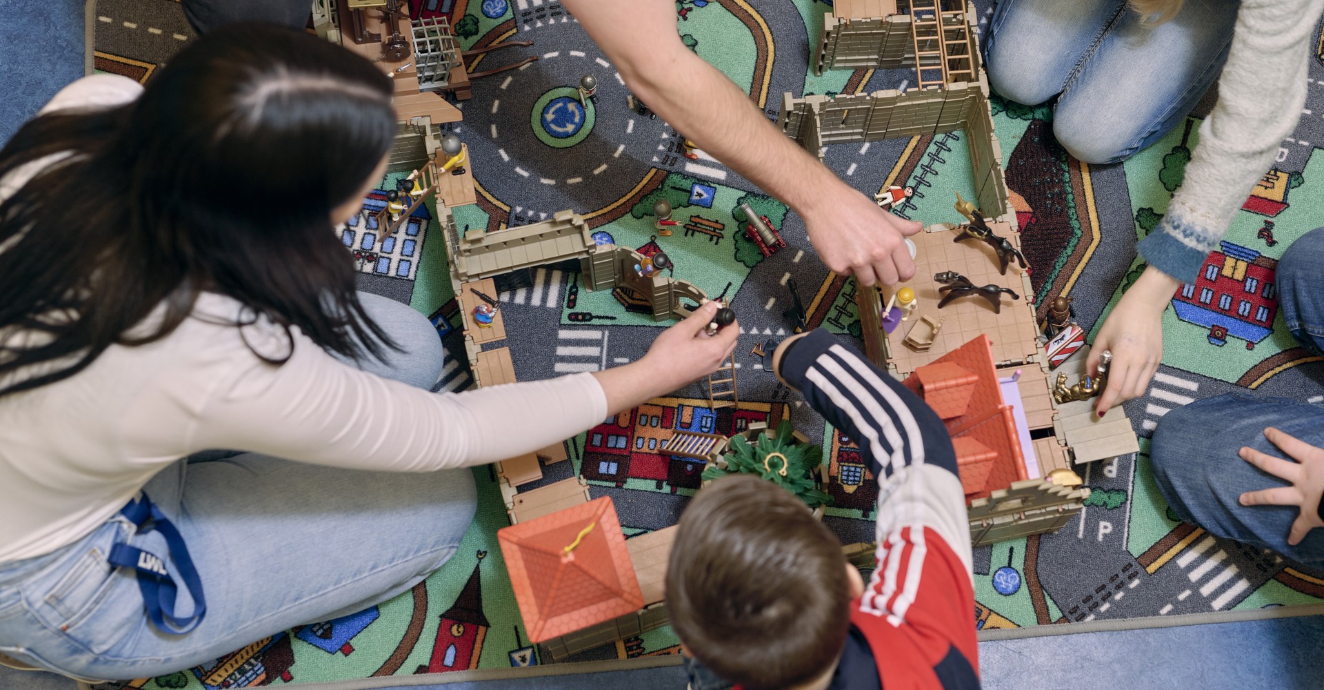 Kinder spielen auf einem Bauteppich.