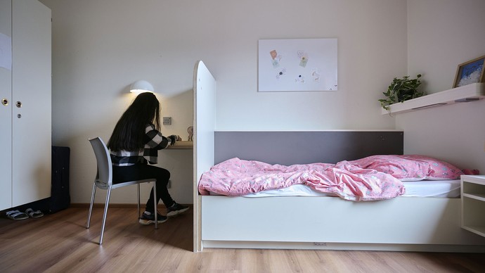 Ein junges Mädchen sitzt in einem Zimmer an einem Schreibtisch. Ein junges Mädchen sitzt in einem Zimmer an einem Schreibtisch.