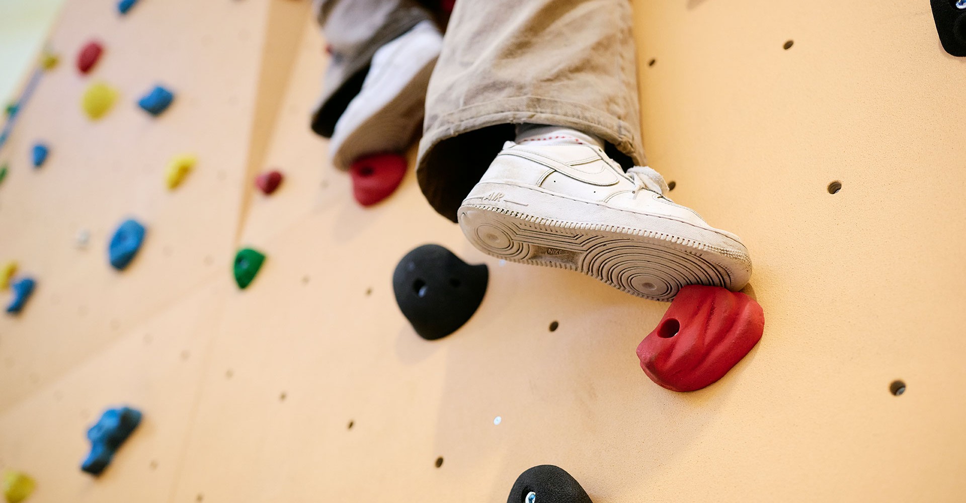 Ein Kind klettert an einer Kletterwand