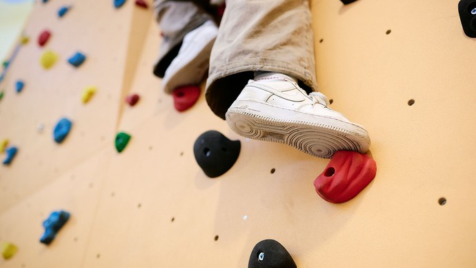 Eine Person klettert an einer Kletterwand. Eine Person klettert an einer Kletterwand.