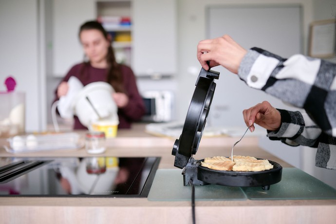 Zwei Mädchen backen Waffeln.