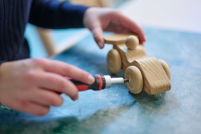 Ein Kind bastelt ein Auto aus Holz.