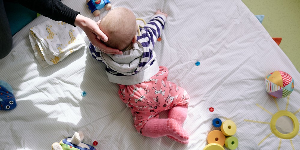 Im Rahmen der Babysprechstunde liegt ein Baby auf einer Spieldecke.