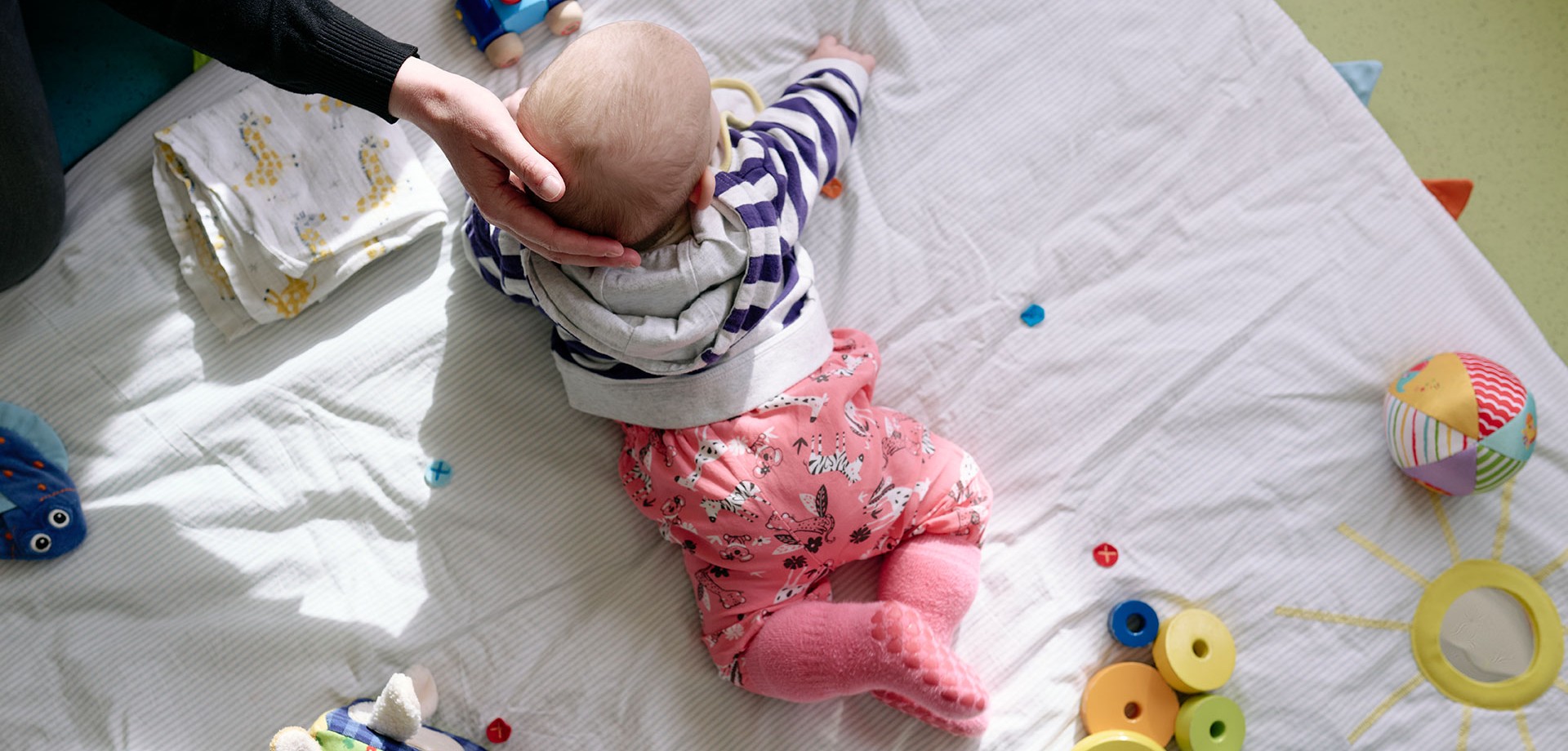 Ein Baby liegt auf dem Bauch auf einer Decke.