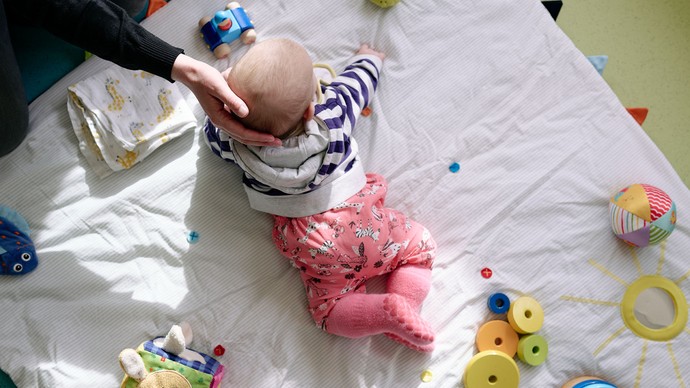 Ein Baby liegt auf einer Spieldecke